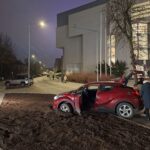 Raudonas automobilis įklimpęs supiltoje žemėje prie simfoninio orchestro pastato