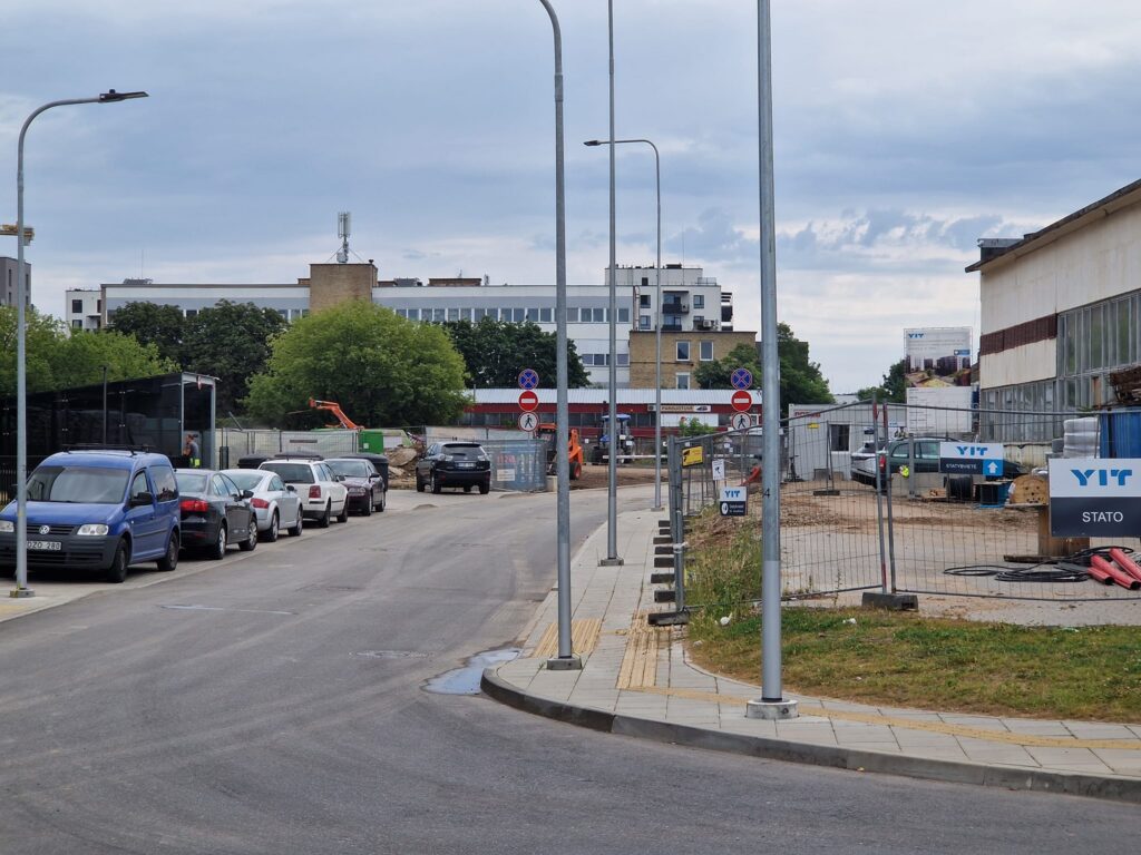 Apšvietimo stulpai siauro šaligatvio viduryje ir bala Laumenų gatvėje